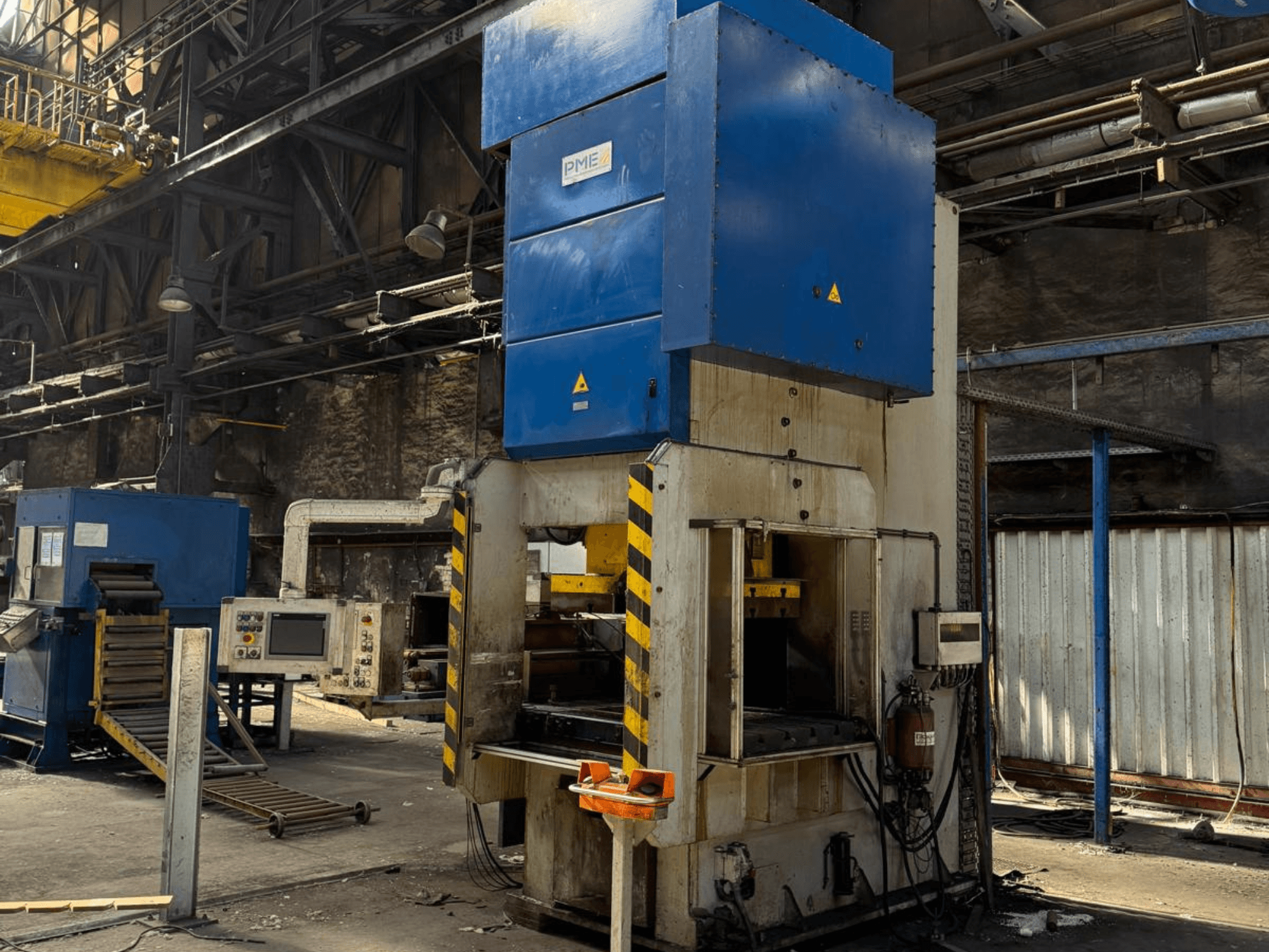 Prasa mechaniczna PME PE 400-1700 C, widok z przodu, przedstawiająca niebieską górną część i podstawę w żółte paski w warunkach fabrycznych.
