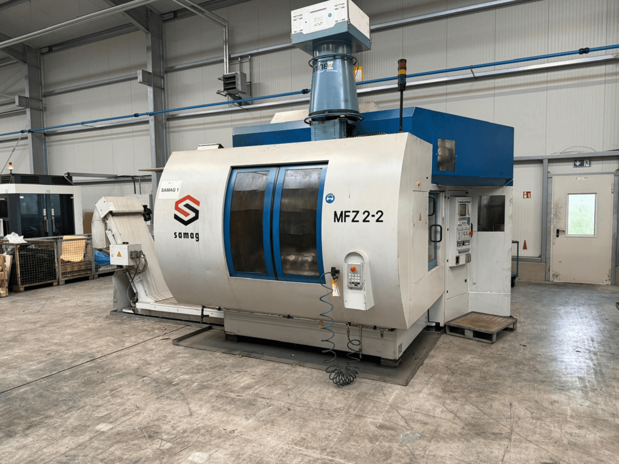 Obrabiarka Samag MFZ 2-2, widok z przodu, pokazujący panel sterowania i niebieski blat, z funkcjami bezpieczeństwa w środowisku przemysłowym.