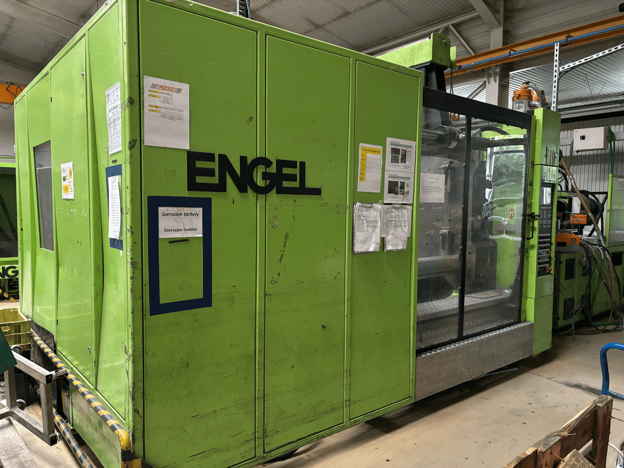 Hydrauliczna wtryskarka Engel DUO 5550/800, widok z przodu, z zieloną obudową i przezroczystym panelem dostępu.