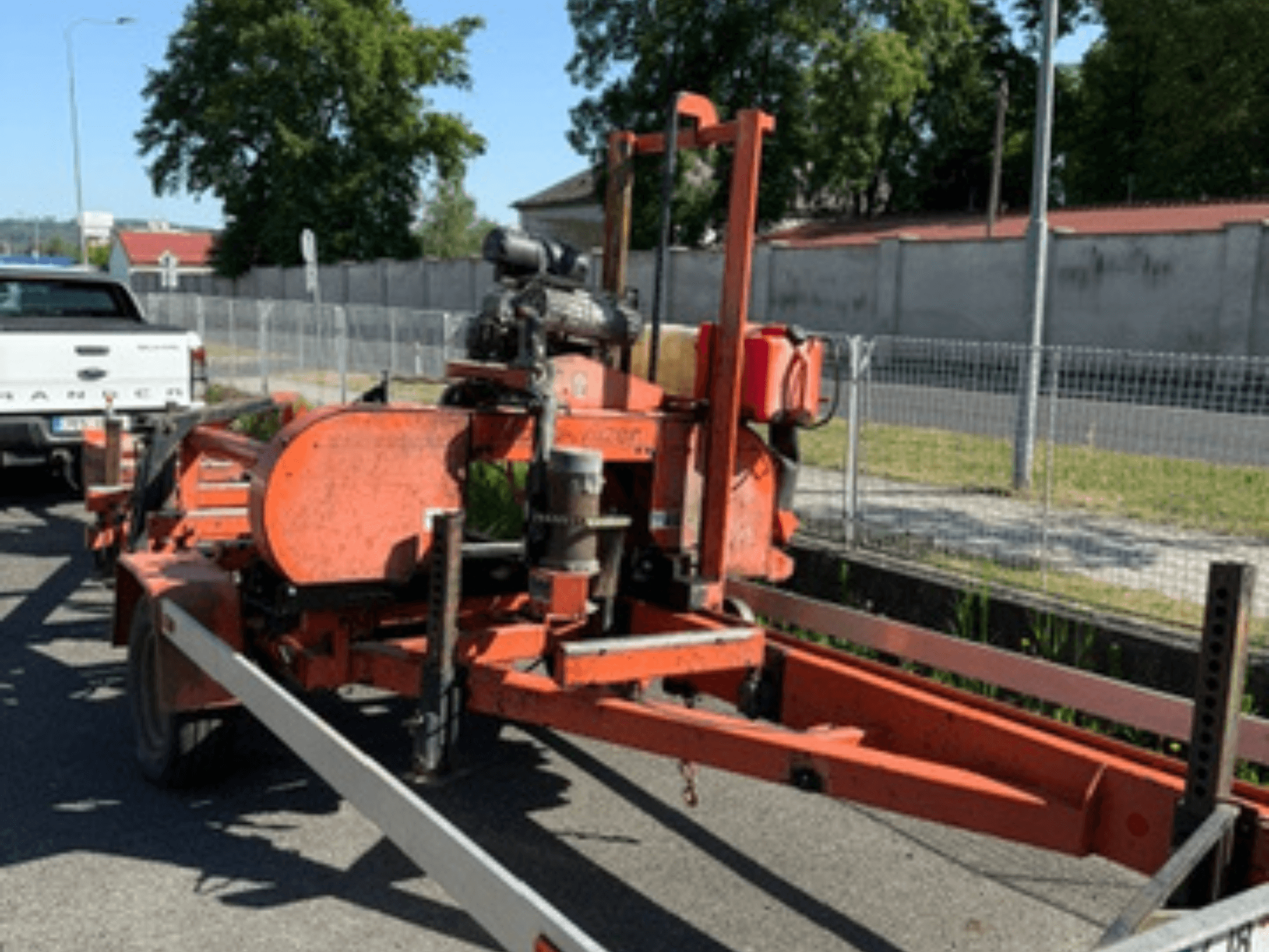 Piła taśmowa do drewna WOOD-MIZER LT40 w kolorze pomarańczowym, widok z boku na przyczepie z widocznymi kołami i elementami silnika.