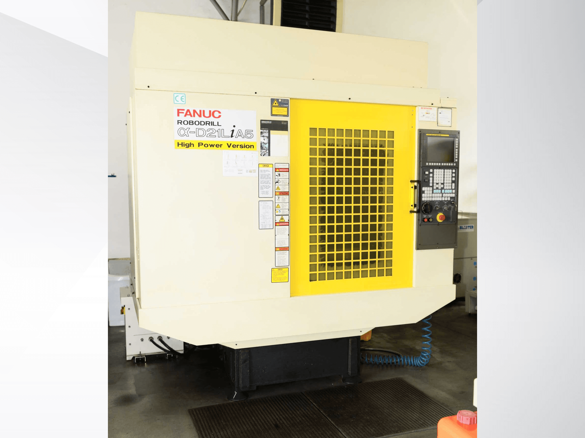 Pionowe centrum obróbcze FANUC ROBODRILL α-D21LiA5 – widok z przodu z żółtą kratką zabezpieczającą i szczegółami panelu sterowania.