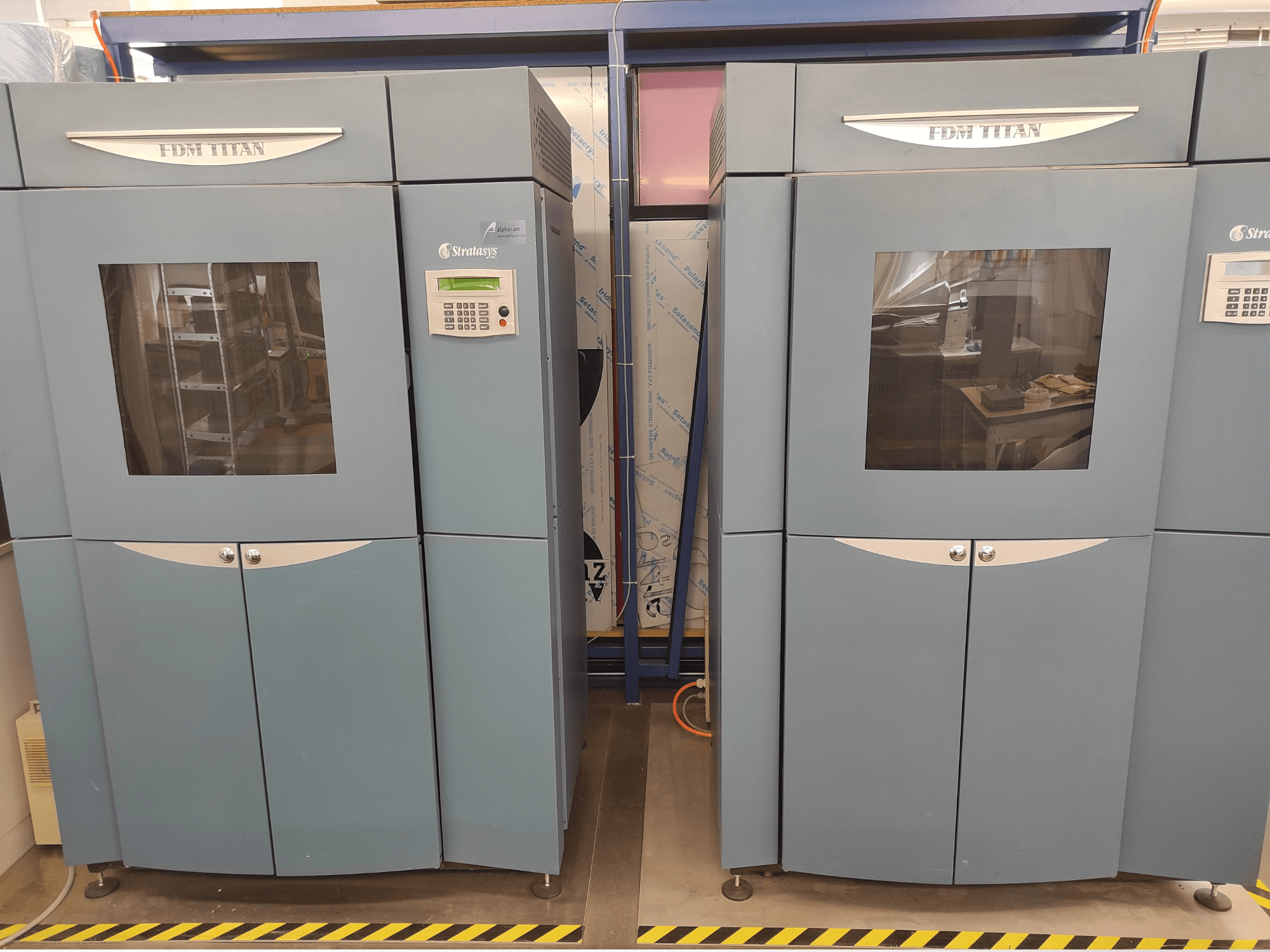 Widok z przodu drukarki 3D Stratasys FDM TitanTI T0031 do druku z tworzyw sztucznych; wyposażona w panel wyświetlacza i przezroczyste okienko.