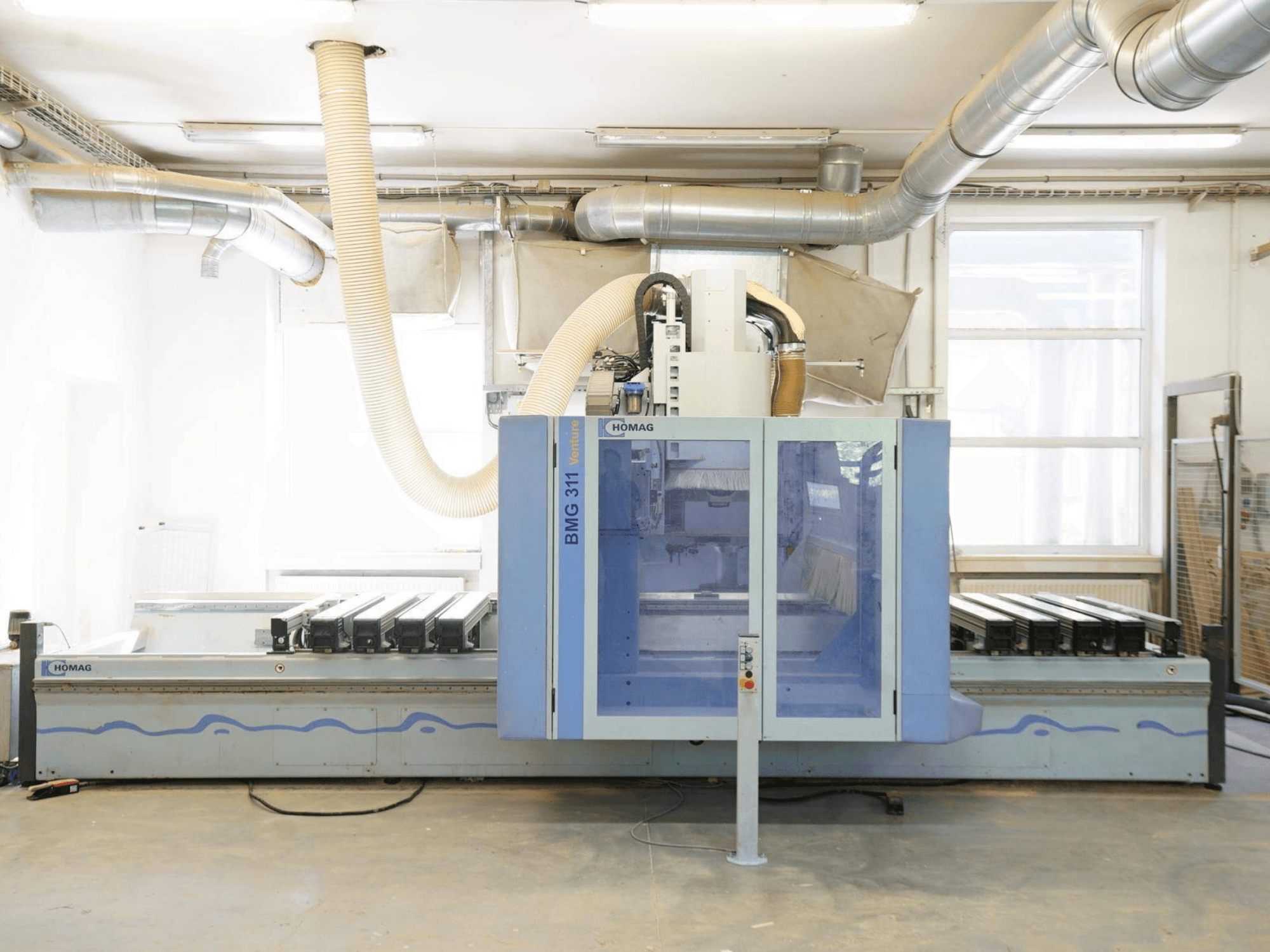 Centrum obróbki drewna CNC HOMAG V BMG 311/42/F/K, widok z przodu, wyposażone w duży stół roboczy i system odpylania.