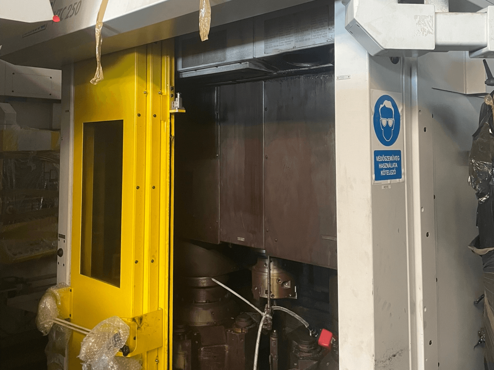 Żółte drzwi wejściowe maszyny ze znakiem bezpieczeństwa, widok z przodu maszyny przemysłowej model Z250, pokazujący elementy wewnętrzne.