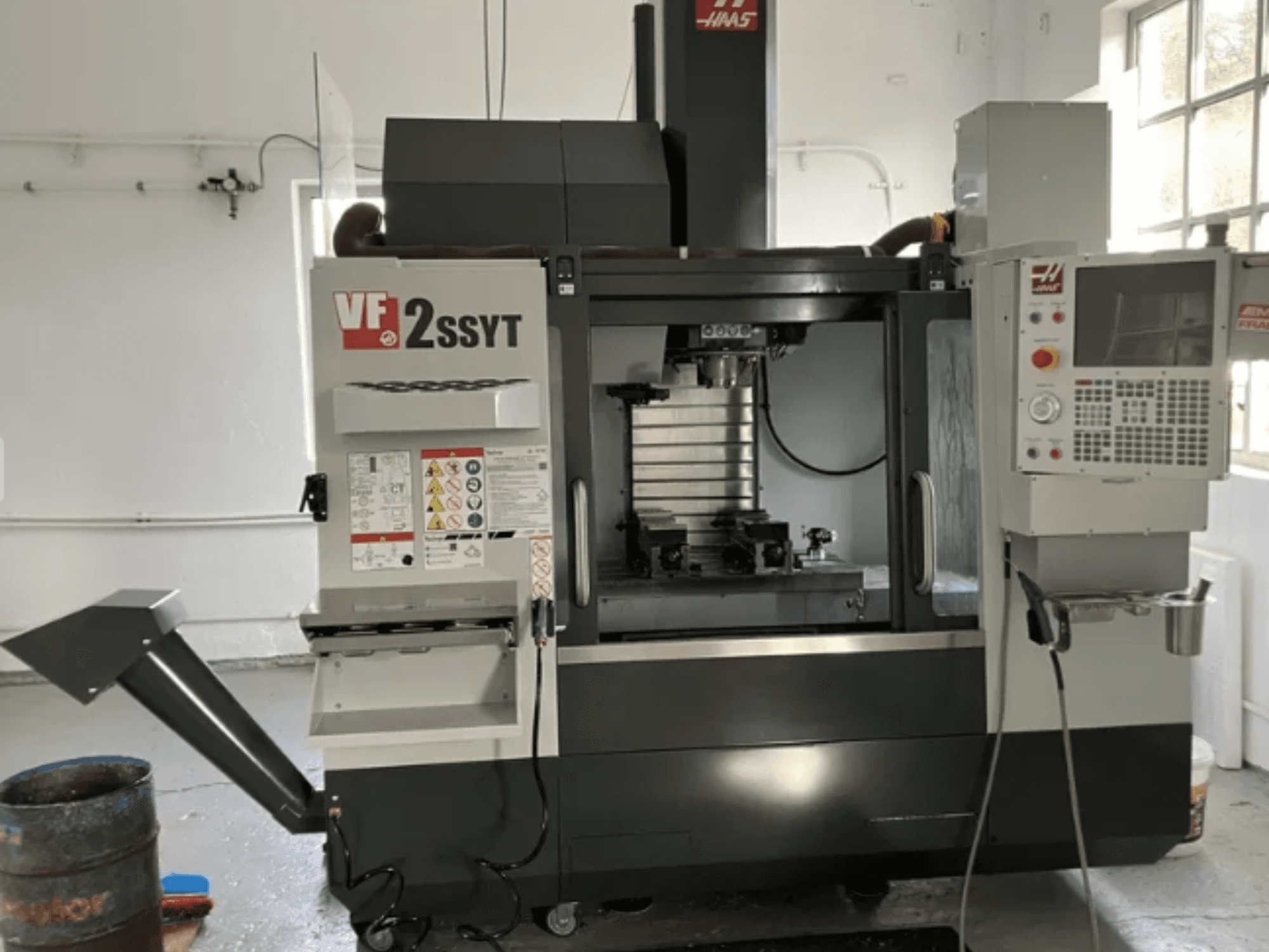 Frezarka CNC Haas VF-2SSYT, widok z przodu, z panelem sterowania, uchwytem narzędziowym i systemem chłodzenia do obróbki metalu.