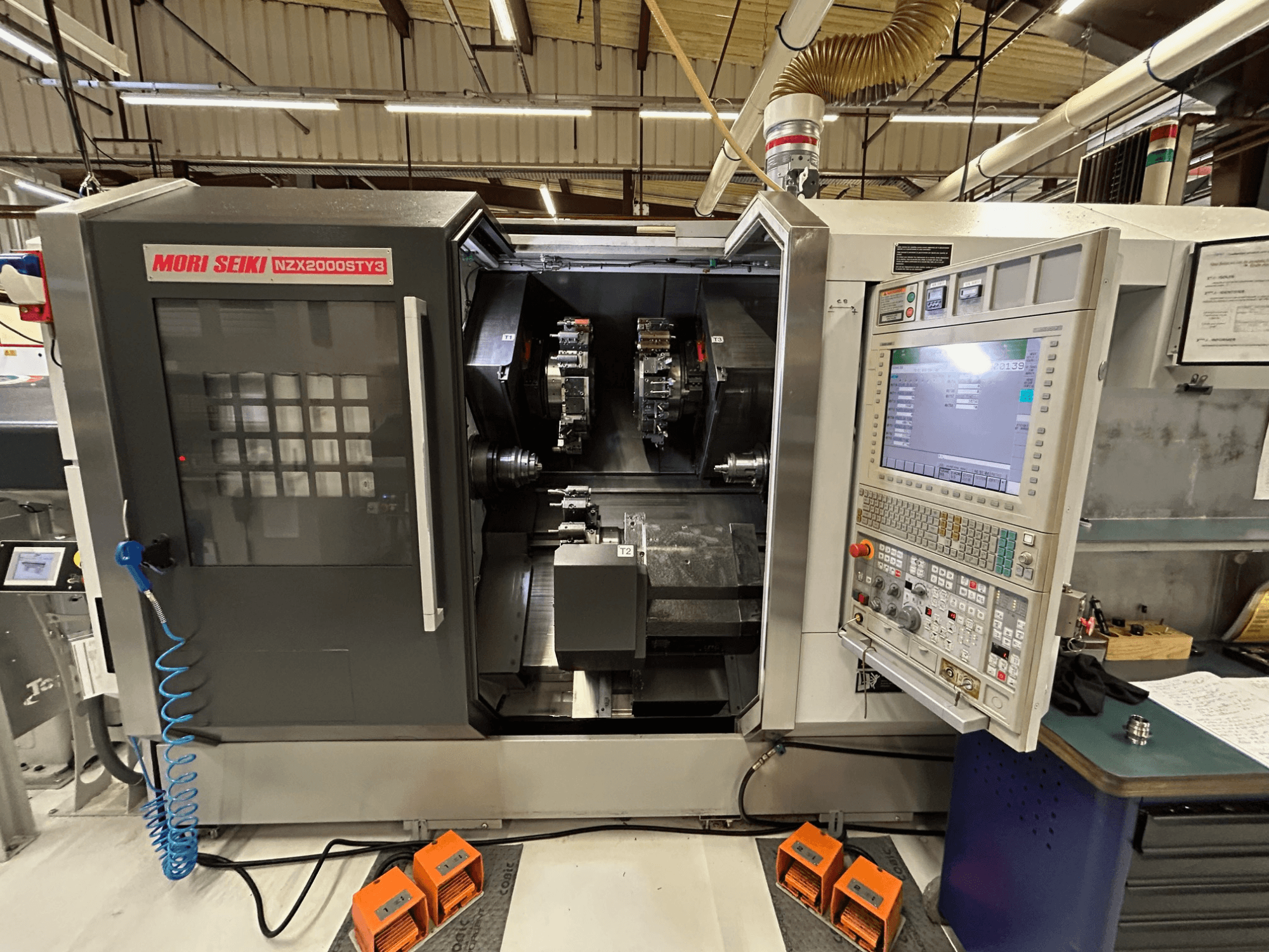 Wielowrzecionowa tokarka MORI SEIKI NZ2000 ST3Y3 – widok z przodu przedstawiający panel sterowania i obszar obróbki.