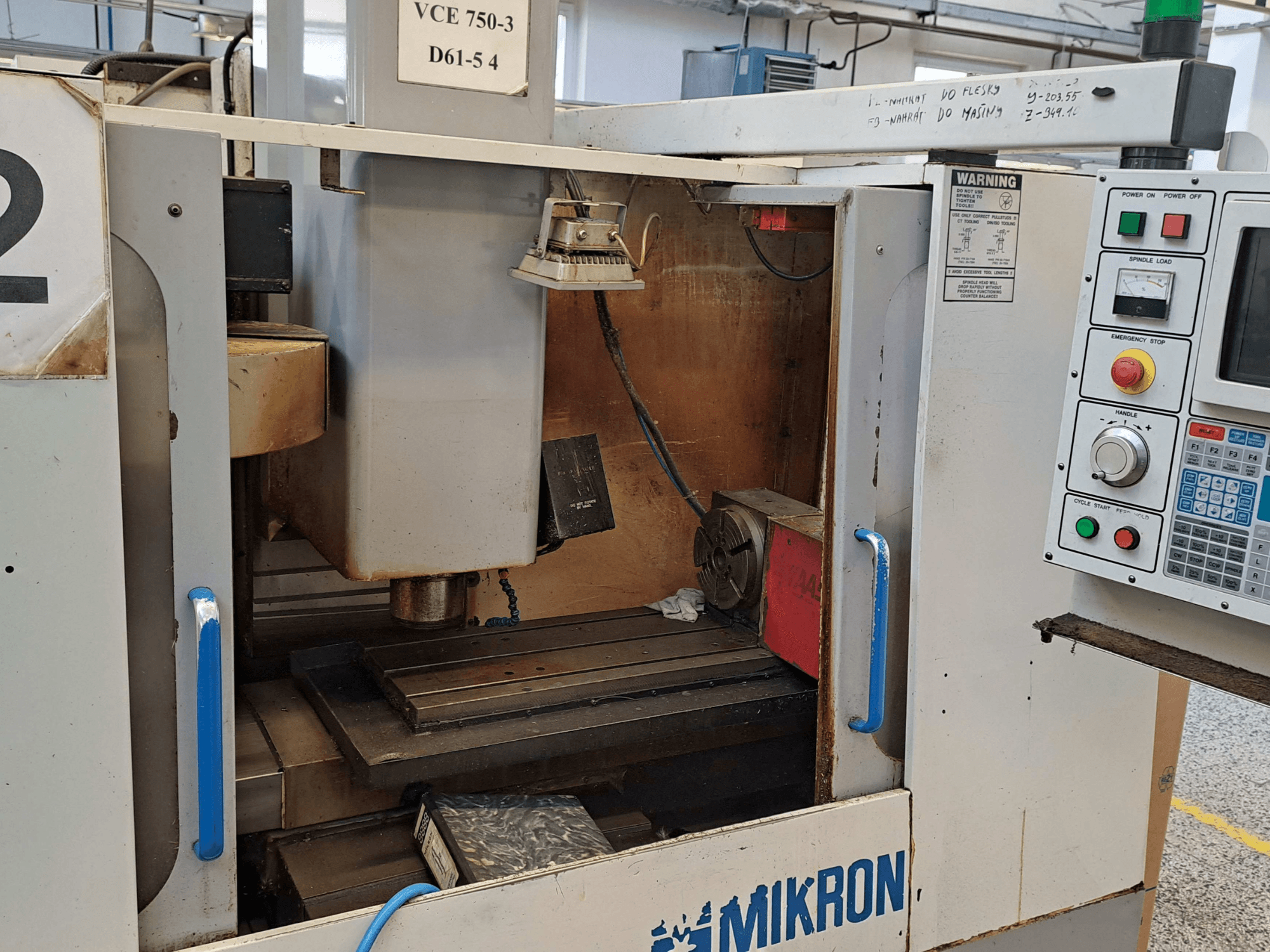 Widok z przodu frezarki Mikron VCE 750-3, pokazujący wrzeciono, panel sterowania i stół roboczy ze szczegółami technicznymi.