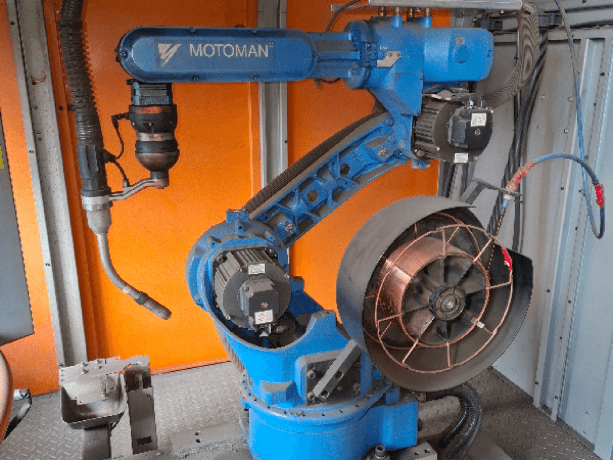 Ramię robota MOTOMAN w kolorze niebieskim, widok z boku, z dołączonym wentylatorem i oprzyrządowaniem, pokazujące szczegóły mechaniczne i połączenia.