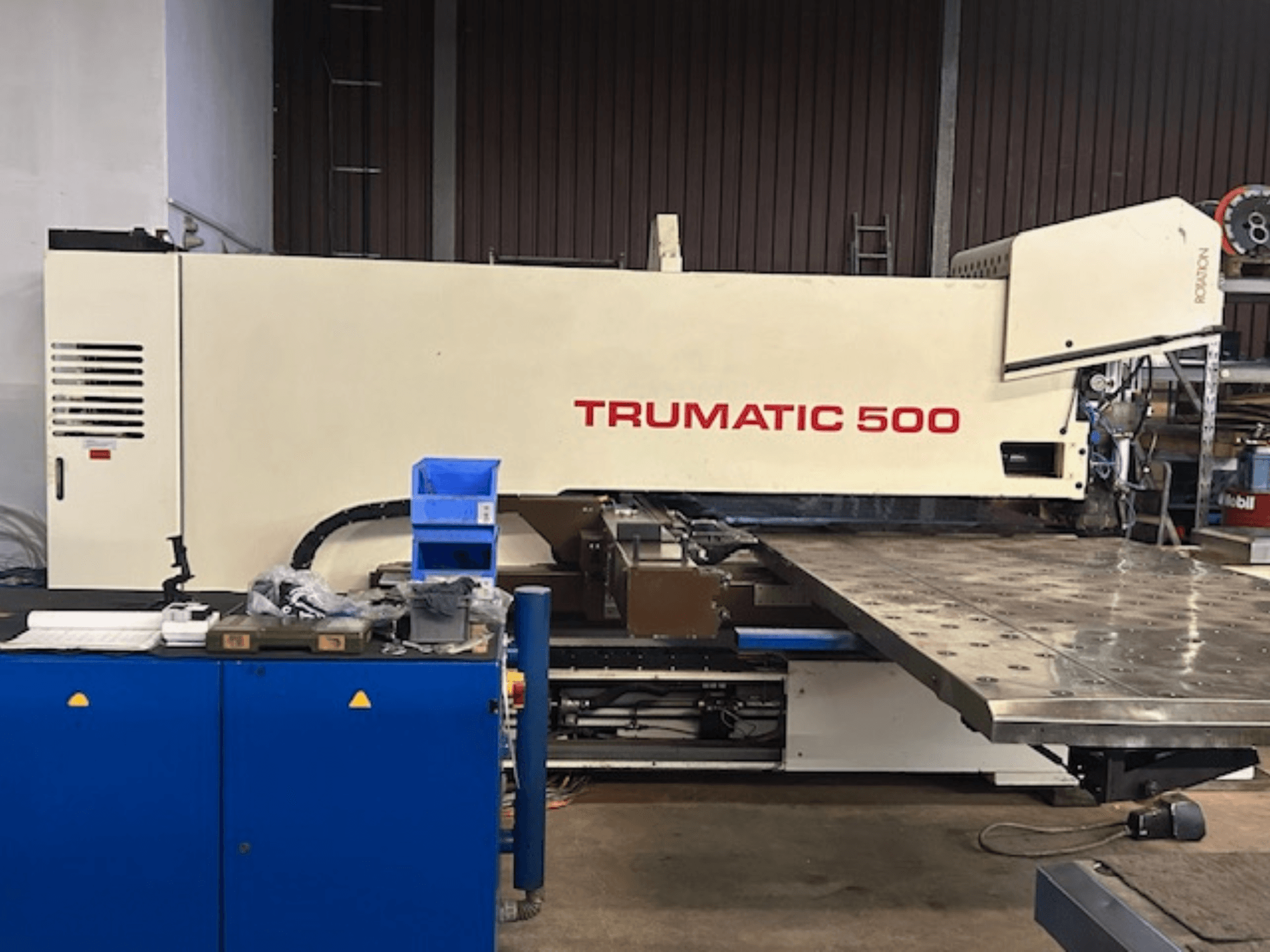 Wykrawarka CNC TRUMPF TRUMATIC 500, widok z przodu, z panelem sterowania i dużym stołem roboczym z perforowaną powierzchnią.