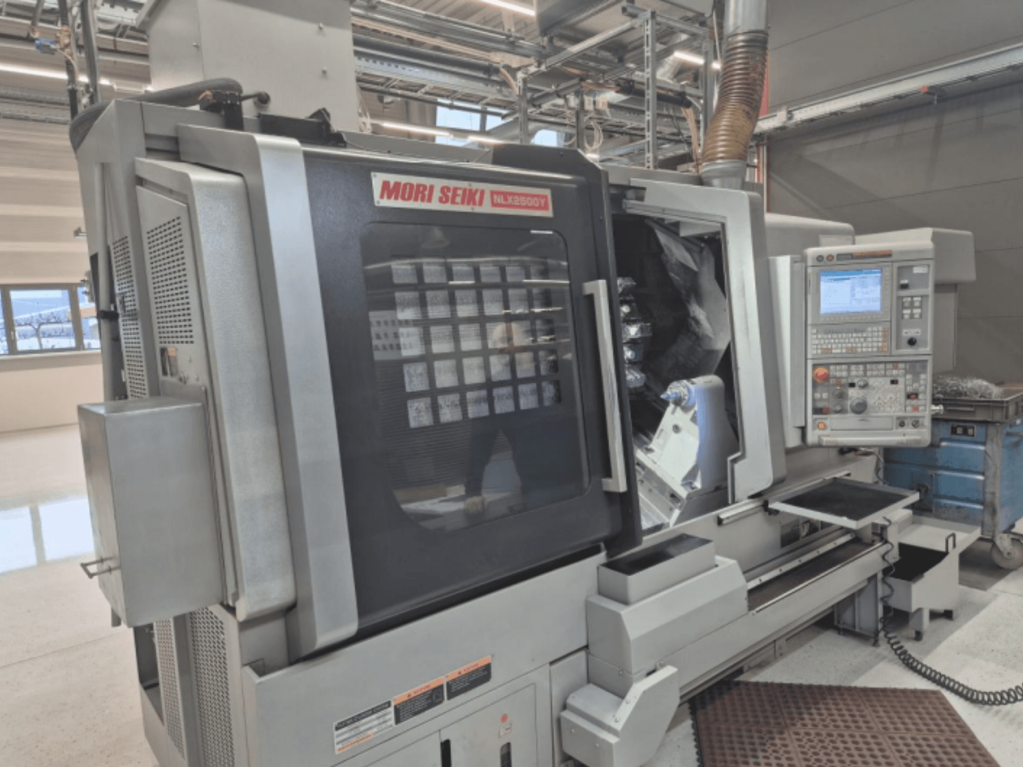 Tokarka CNC MORI SEIKI NL2500Y w ustawieniu fabrycznym, widok z przodu przedstawiający panel sterowania i komorę przedmiotu obrabianego.