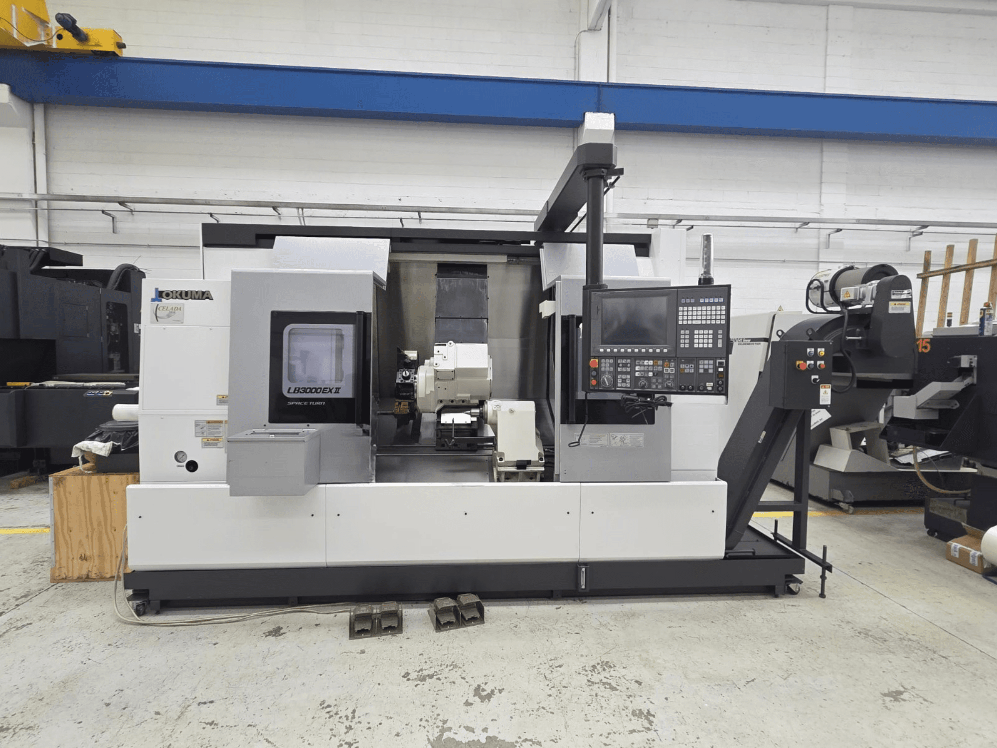 Okuma LB 3000 EXII tokarka pozioma pokazana z przodu, z panelem sterowania i uchwytem narzędziowym.