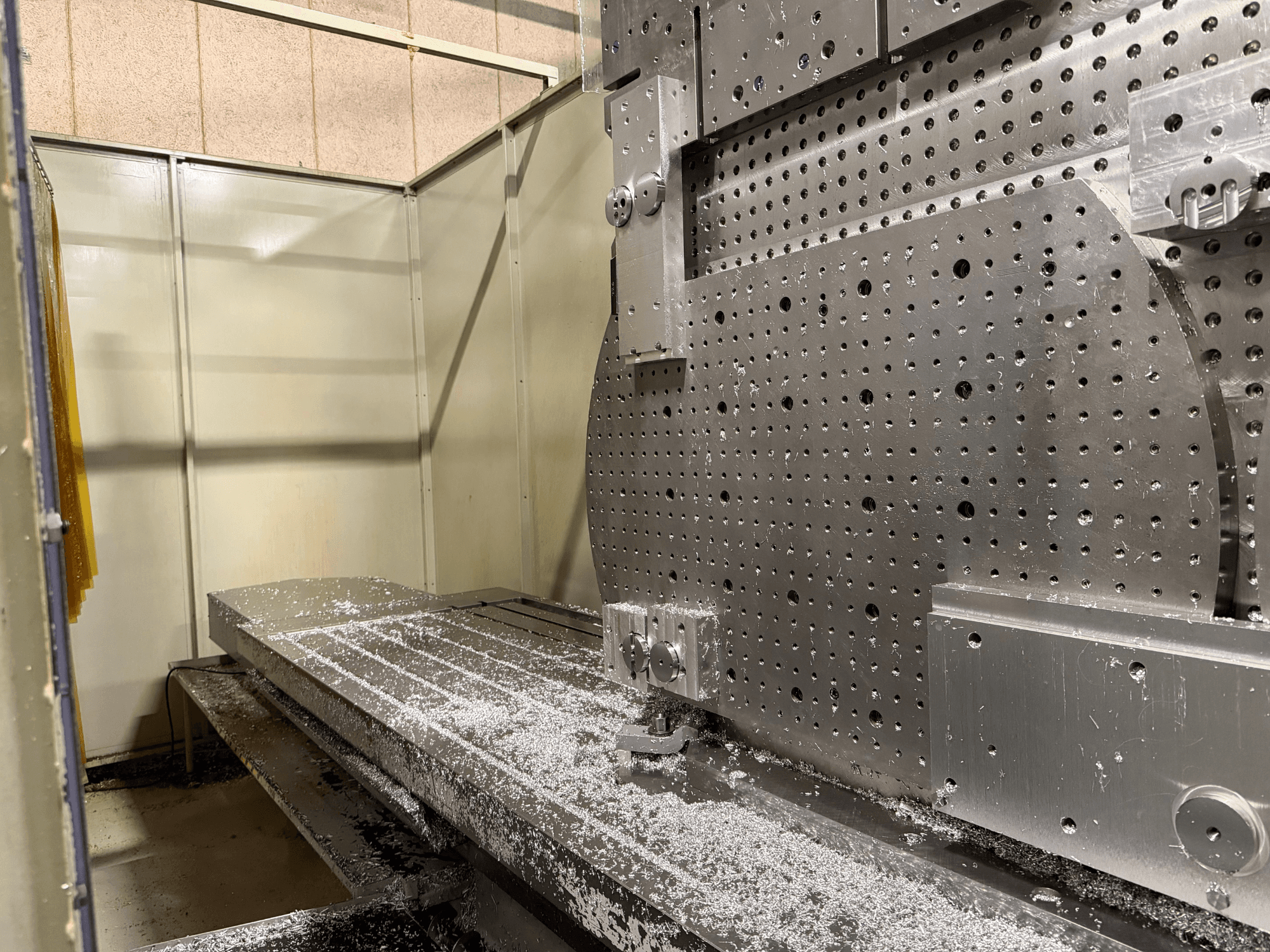 Widok z przodu uniwersalnego centrum obróbczego KIHEUNG KNC-U1000 w zbliżeniu, przedstawiający metalowy stół roboczy z aluminiowymi wiórami.